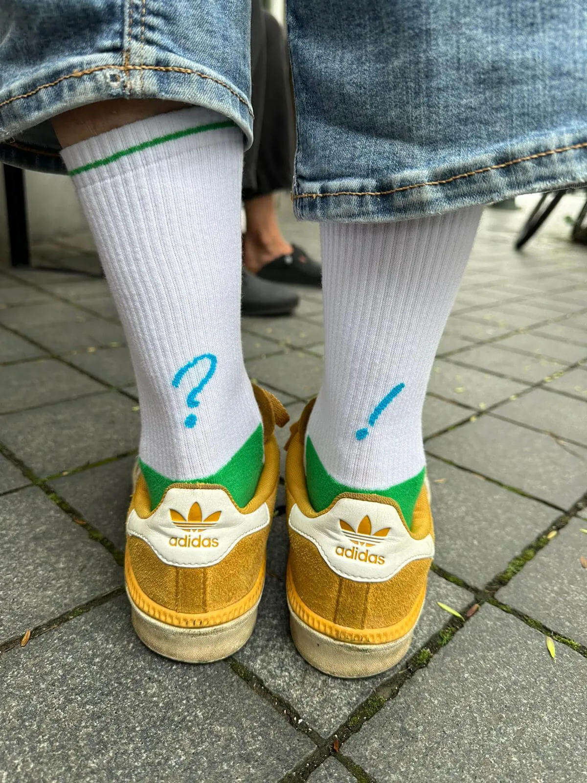 Person wearing the '?!' socks and yellow Adidas shoes